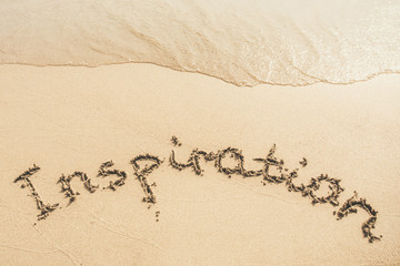 Inspiration text written on the sand