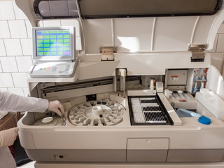 the girl in the lab puts the serum samples in a medical device for analysis. Machine automatic...