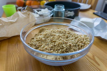 Close up of products for preparing cheesecake, a tray, cream, cream cheese, a bowl of cracked biscuits. Chain of citrus.