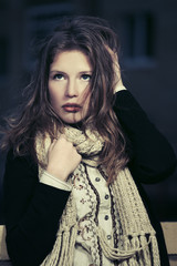 Fototapeta premium Sad young fashion girl in white knitted scarf walking outdoor
