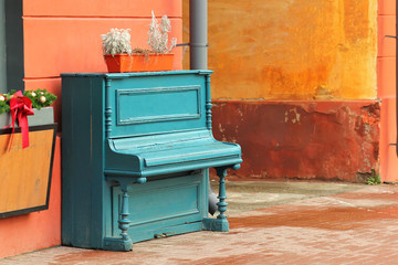 Vintage weathered aquamarine piano outdoor in the street downtown