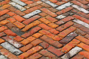 Old weathered orange brick pavement downtown, close up background texture, perspective view, horizontal