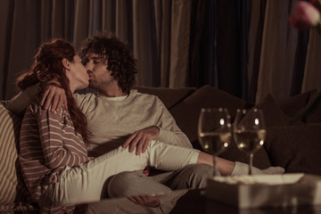 Naklejka premium heterosexual couple kissing on sofa in evening