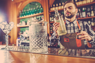 Barman making an alcoholic cocktail at the bar counter on the bar background