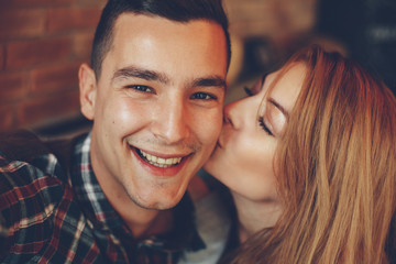 Closeup of girl kissing her boyfriend on the cheek - obrazy, fototapety, plakaty