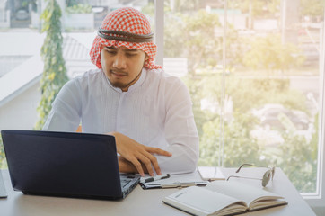 young Arabian business man developing a new idea and working with laptop computer, clipboard and document on desk at home office, successful, financial, business technology and investment concept