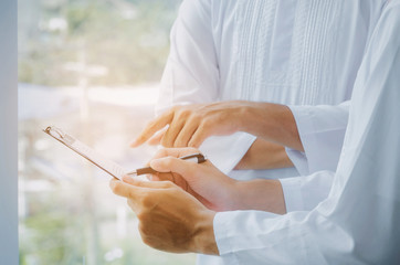 two young Arabian business man signing contract or agreement document after finishing up meeting in office building or construction site, life insurance, financial, successful deal, investment concept