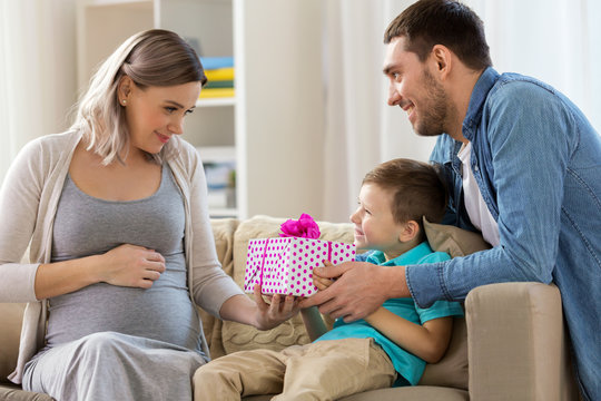 family giving present to pregnant mother at home