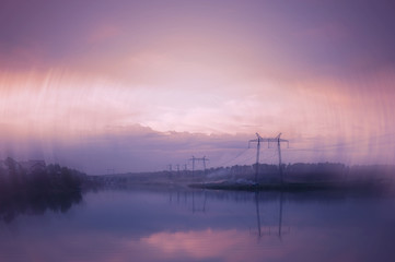 Evening misty landscape of the countryside. A magenta sunset. Purple river in the fog. Wires of electric voltage.