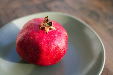 Ripe juicy pomegranate on a plate on a wooden surface of a table