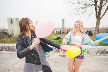 Two beautiful blonde and brunette girls playing with baloons