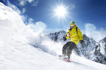 A snowboarder on the top of the mountain. He is sliding down a mountain slope, ski season and great...