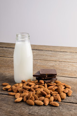 milk in bottle, chocolate and almond on wooden