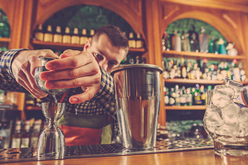 Barman making an alcoholic cocktail at the bar counter on the bar background