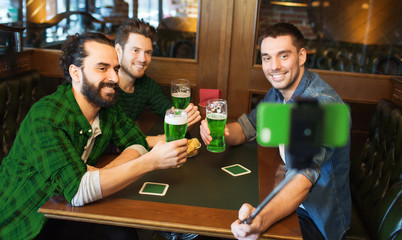 friends taking selfie with green beer at pub