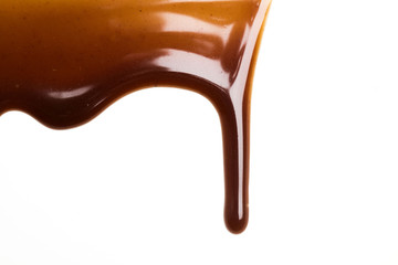 Chocolate caramel sauce drop on a plain white backround - obrazy, fototapety, plakaty