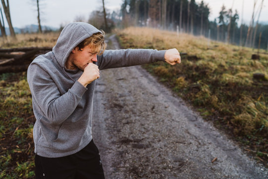 Young man shadow boxing in Austria in a forrest at sunrise