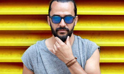 close up of man in sunglasses touching beard