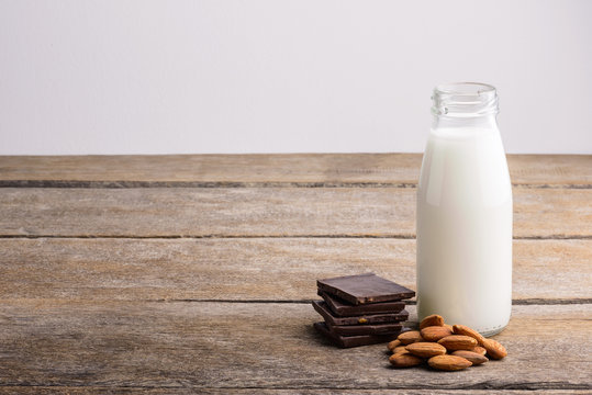milk in bottle, chocolate and almond on wooden