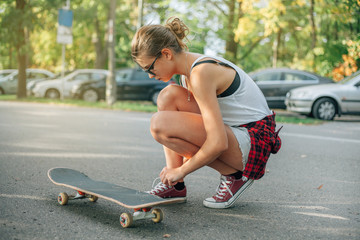Young woman tie shoes. Skateboard girl.