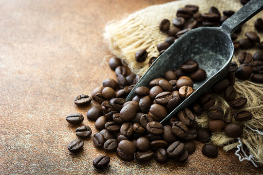 Roasted coffee beans and spoon on brown rustic background.Copyspace