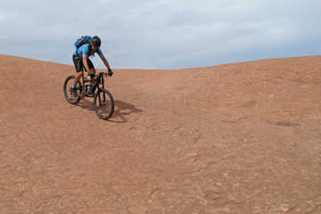 Fototapeta premium Mountain biker riding downhill the famous Slickrock trail, Moab, Utah, USA