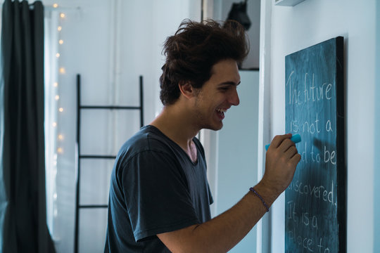 Cheerful man at blackboard at home