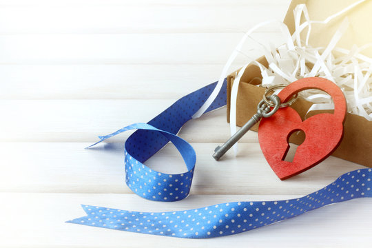  holiday day of all lovers/ heart symbol and padlock with a key next to an open gift on the table 