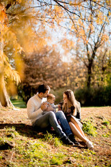 Young family sitting on the ground in autumn park