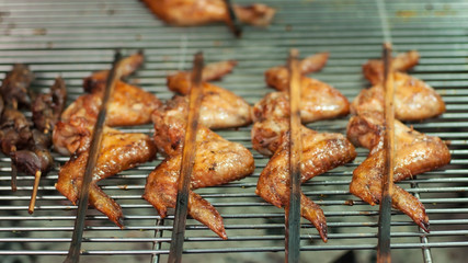 Roasted chicken wings sticks lay on stainless sieve, Thailand food street.