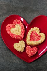 Fototapeta na wymiar Homemade Rice Krispie Crispy hearts in red plate / Valentines day food background