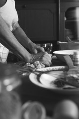 Senior female baker kneading dough in kitchen. Black And white.