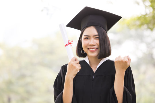 Young Asian Woman Students wearing Graduation hat and gown, Garden background, Woman with Graduation Concept.