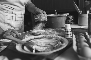 Senior female baker kneading dough in kitchen. Black And white.