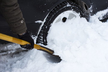  a man cleaning a car from a snow shovel
