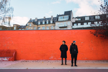 Two men at orange wall
