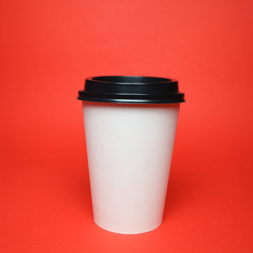 Paper coffee container with black lid on red background. Takeaway drink container. Template of drink cup for your design. Can put text, image, and logo.
