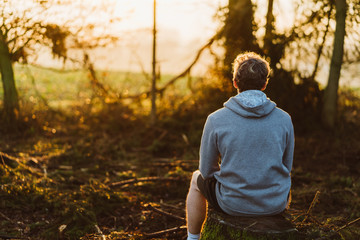 Young man meditating at sunrise in a forrest in Austria