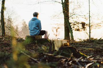 Young man meditating at sunrise in a forrest in Austria