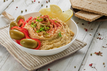 Hummus of chickpeas with olives on a rustic wooden table. A hearty snack from Eastern countries