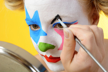 Clown schminkt sich zu Karneval, Fastnacht oder Fasching