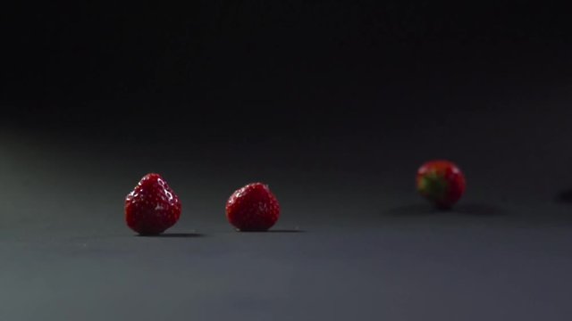The strawberry berries singly fall on the gray surface.