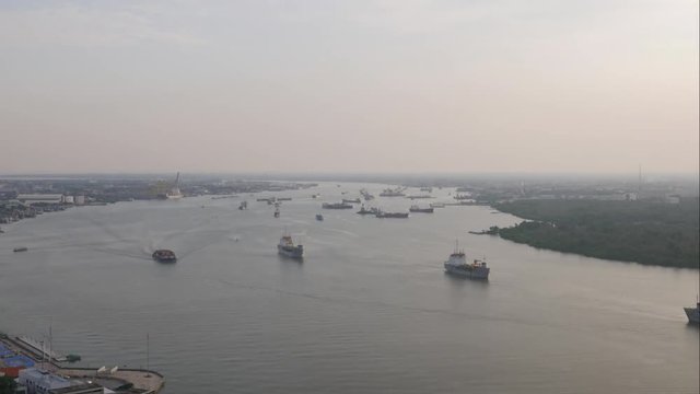 Time-lapse Aerial view of tugboat and Cargo transport ship passing industrial port area in river. at sunset time.