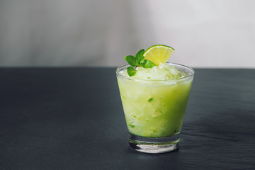 Cocktail juice with lime, mint and ice. Bar drink accessories on black table background.