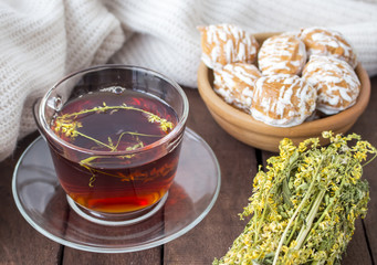 The amber Cup of tea with cakes in a plate on a brown wooden surface