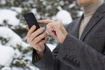 close-up of a businessman in winter in the forest with a phone in a gnome cap
