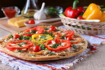Cooked pizza, vegetables and ingredients are on the table.