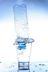 Empty bottle in glass of water with splashing and reflection.