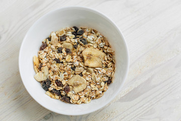 Top view of cereal breakfast with dried banana and raisins. Healthy vegetarian snack.