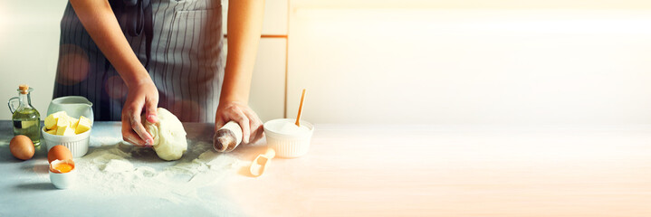 Vrouwelijke handen kneden van deeg, bakken achtergrond. Kokende ingrediënten - eieren, meel, suiker, boter, melk, deegroller op witte keuken. Ruimte kopiëren. Banner